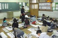 書道をする児童たちと先生の写真