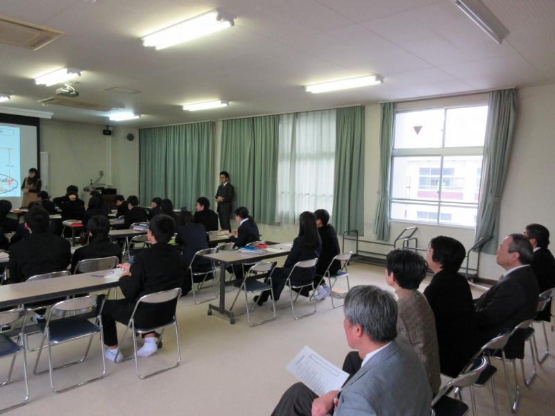 授業中の生徒と、後ろで授業参観をする委員の写真