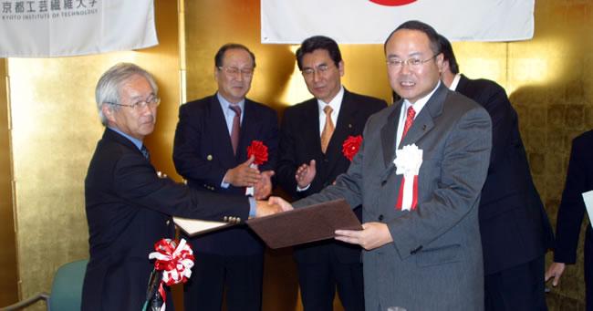 包括協定に調印し、協定書を取り交わす京都工芸繊維大学 江島学長（写真左）と中山京丹後市長（写真右）