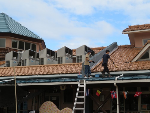 屋根を掃除する保護者