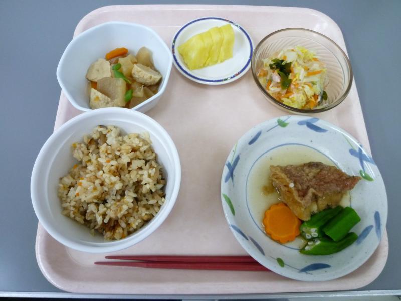 給食（カレイの揚げたもの、炊き込みご飯、筑前煮、たくあん、サラダ）の写真
